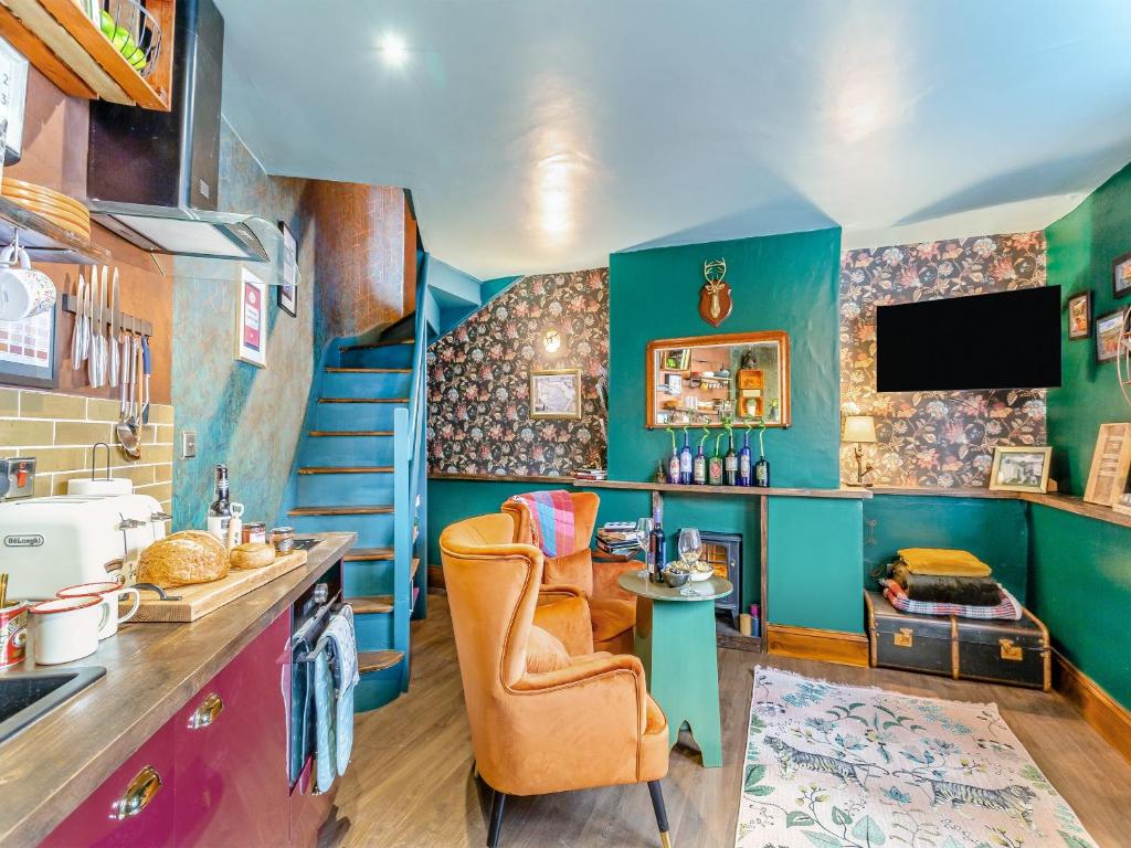 a kitchen with blue and green walls and a staircase at Buttress Retreat in Hebden Bridge