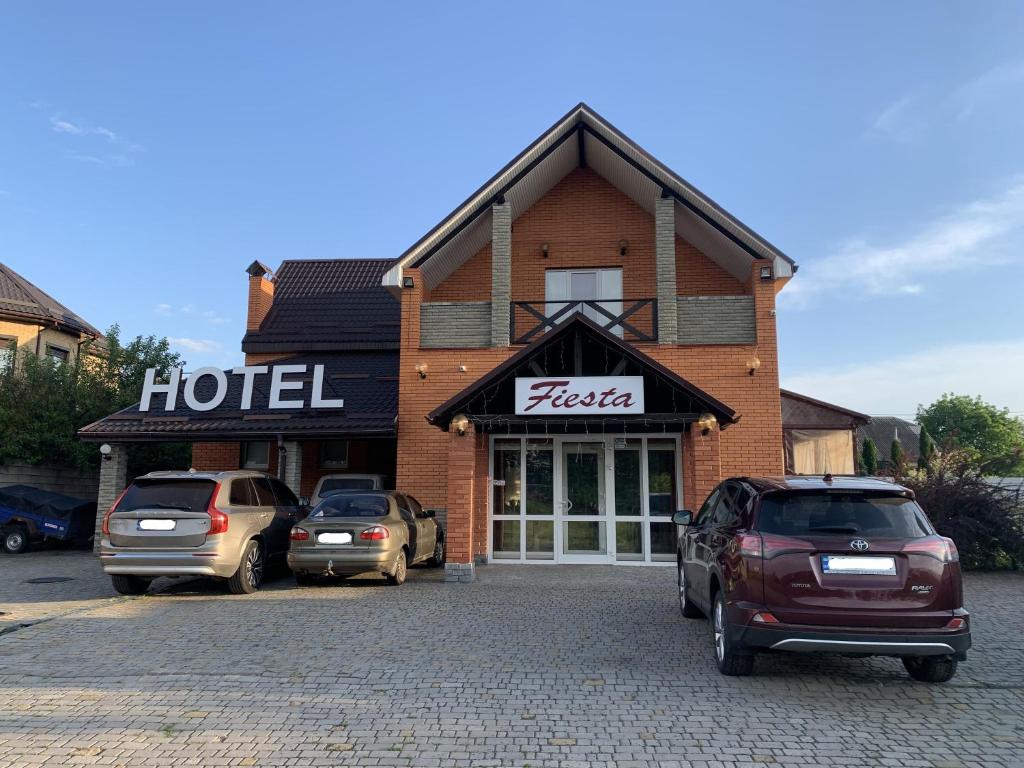 un hotel con dos coches estacionados frente a él en ФИЕСТА en Hora