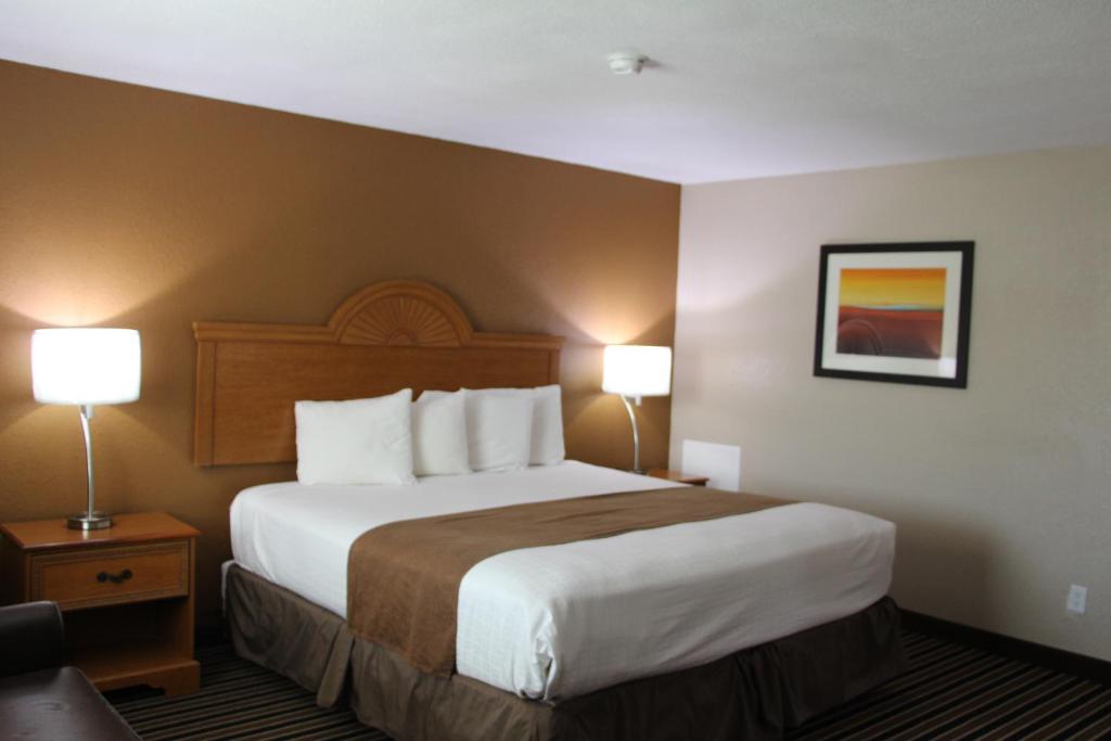 a hotel room with a large bed and two lamps at Westbridge Inn & Suites in Clinton