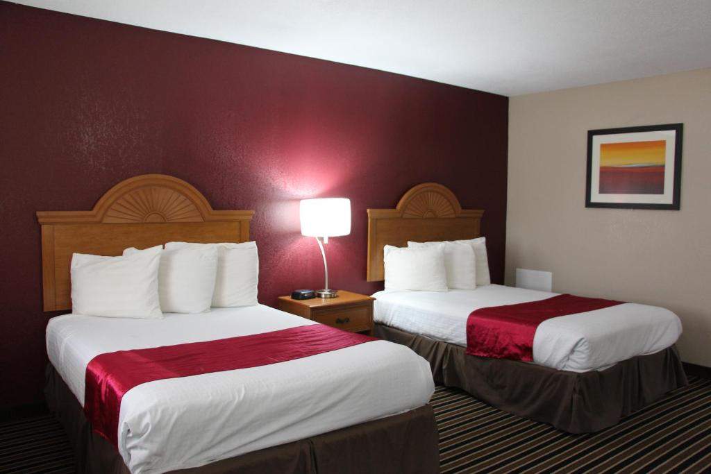a hotel room with two beds and a lamp at Westbridge Inn & Suites in Clinton