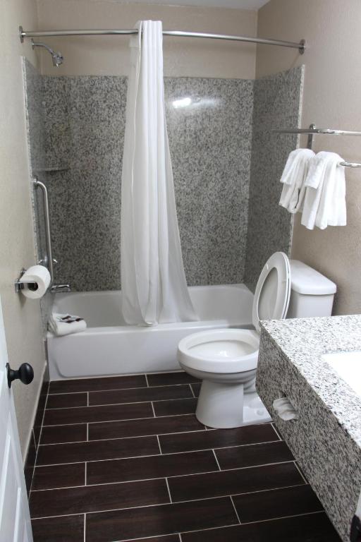 a bathroom with a toilet and a tub and a sink at Westbridge Inn & Suites in Clinton