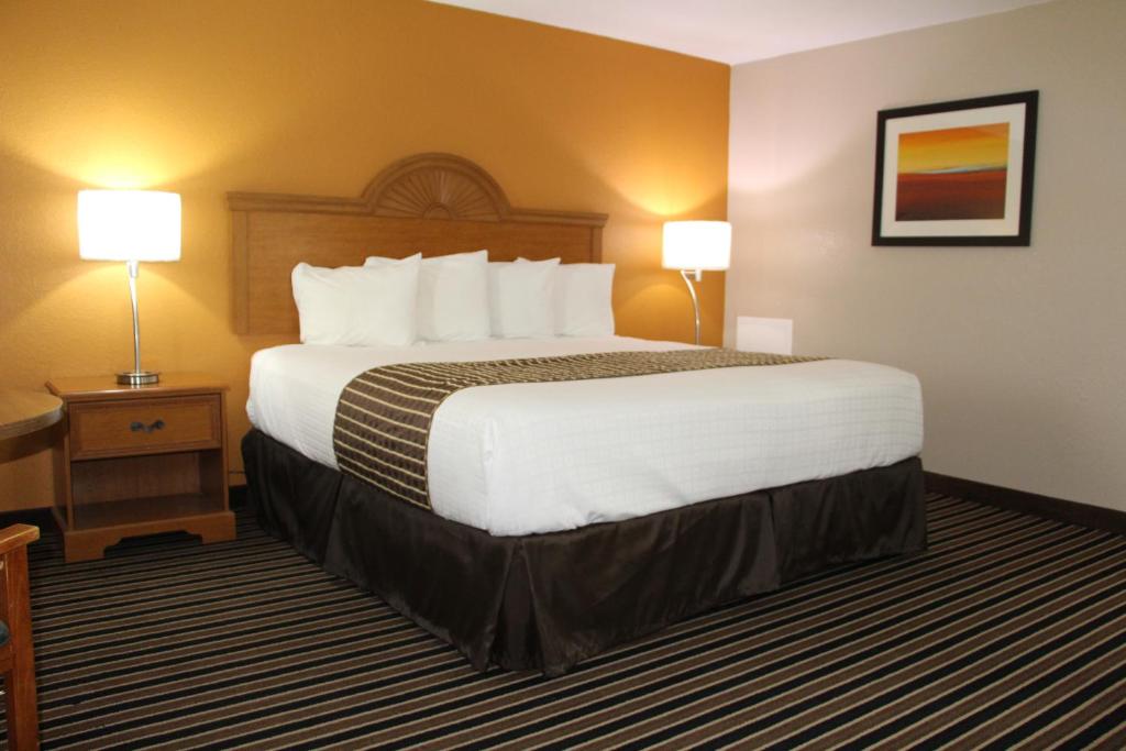 a hotel room with a large bed and two lamps at Westbridge Inn & Suites in Clinton
