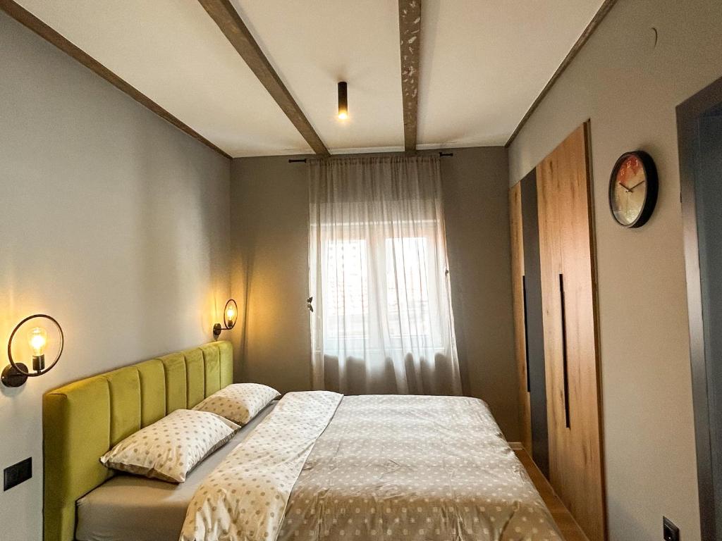a bedroom with a bed with a yellow headboard and a window at Old Town Premium Apartments in Mostar