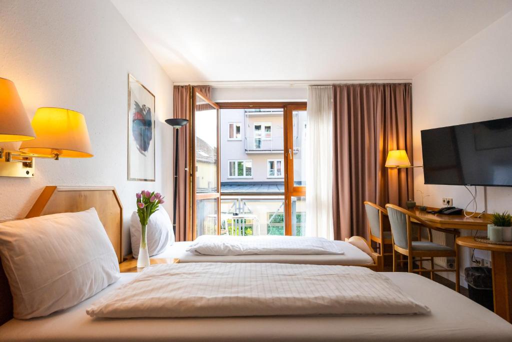 a hotel room with two beds and a desk and a window at CityHotel Feuerbach in Stuttgart