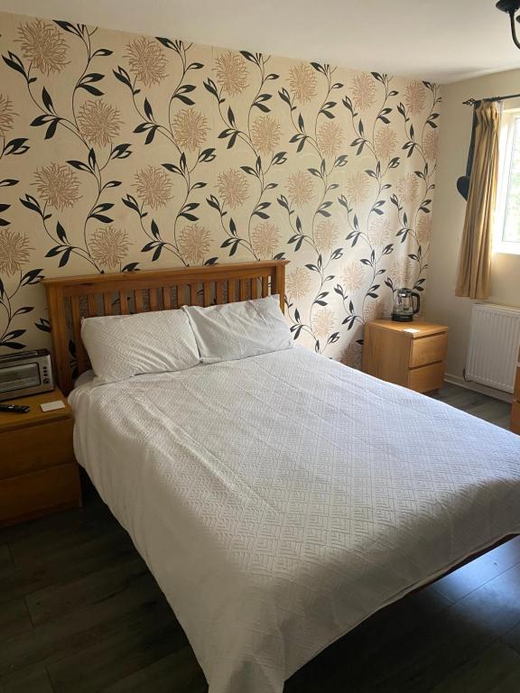 a bedroom with a bed with a floral wallpaper at LA Mansion in Wednesbury