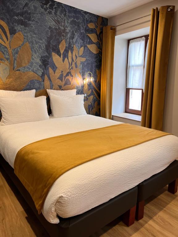 um quarto com uma cama grande e um cobertor amarelo em Logis Hôtel de france em La Côte-Saint-André