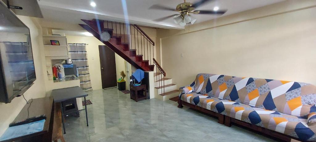 een woonkamer met een bank en een trap bij Affordable Home stay with 3 bedroom near CCLEX in Dapitan