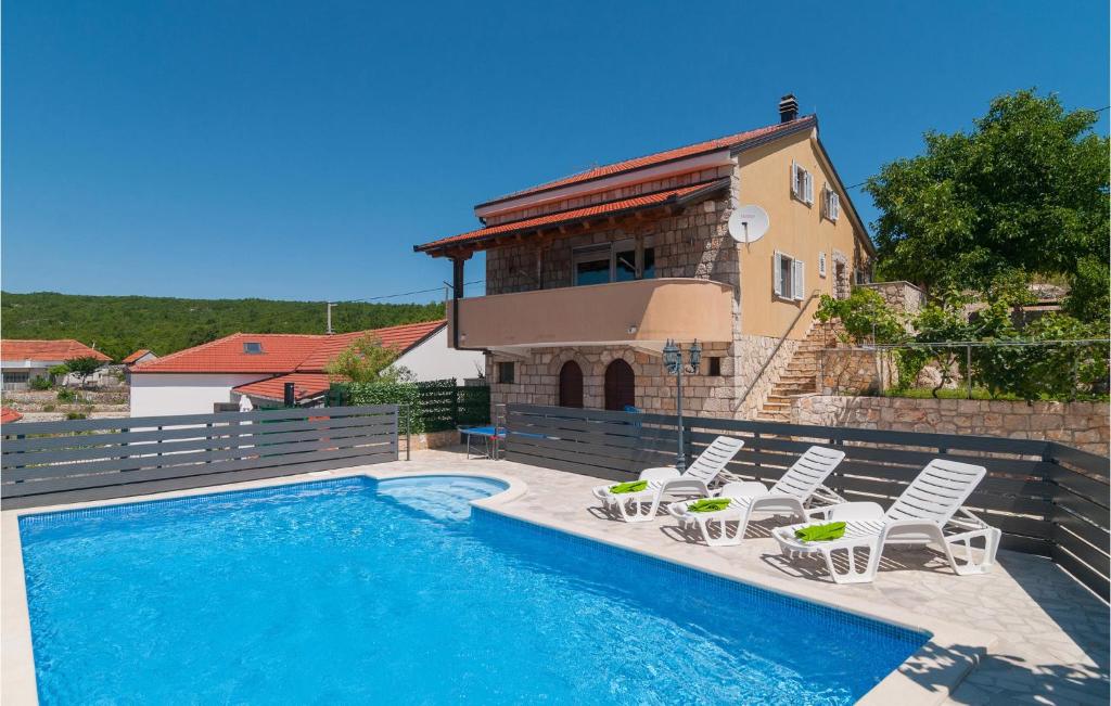 a swimming pool with chairs and a house at Nice Home In Slivno With Outdoor Swimming Pool in Slivno