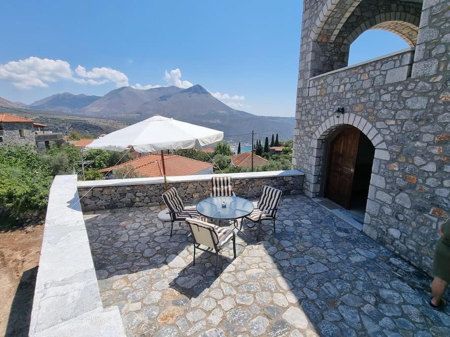 a patio with a table and chairs and an umbrella at Castle in Oitylo in Oítilon