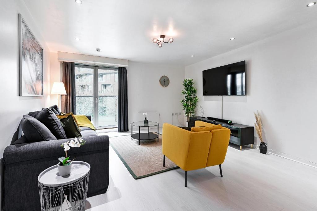 a living room with a couch and yellow chairs at Khayat Homes - The Cosmo - Two Bed in London