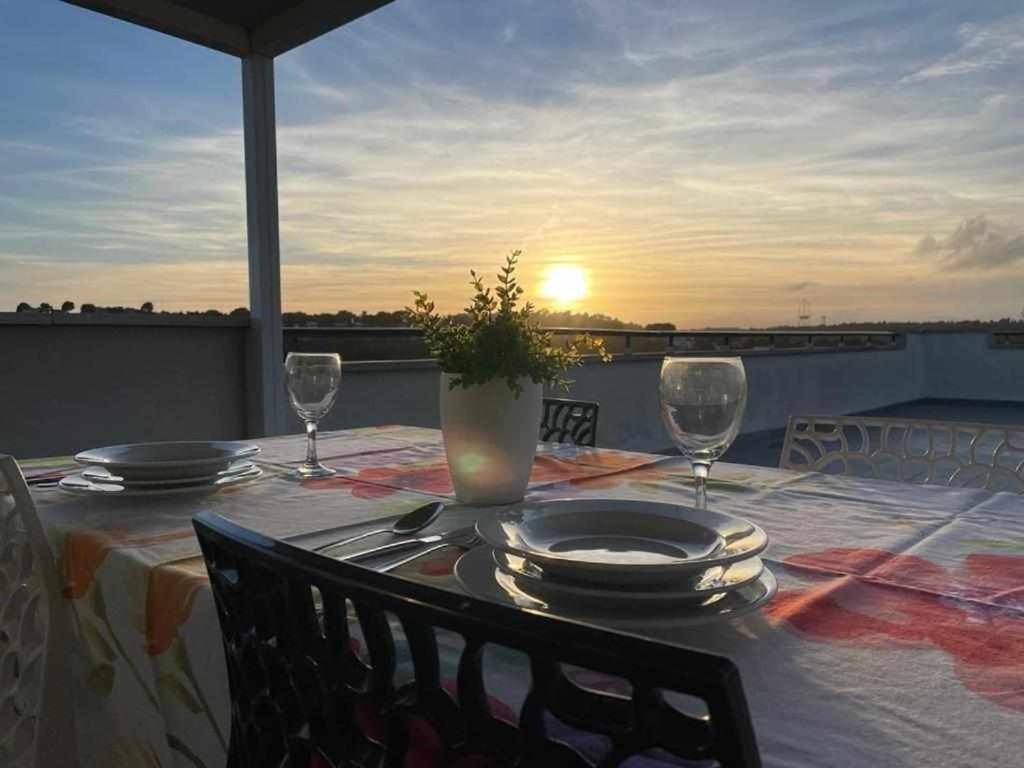 a table with plates and wine glasses on a balcony at Aimar Atico duplex Playa la Pineda Port Aventura in La Pineda