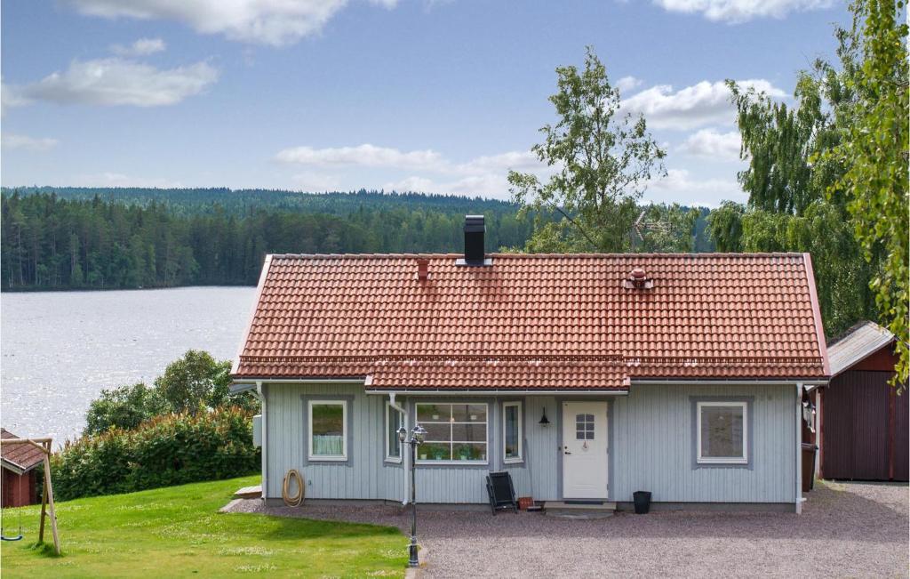 a small white house with a red roof next to a lake at Amazing Home In Idkerberget With House Sea View in Idkerberget