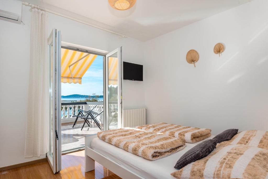 a white bedroom with a bed and a balcony at Apartment and Rooms Dalmatiko in Vodice