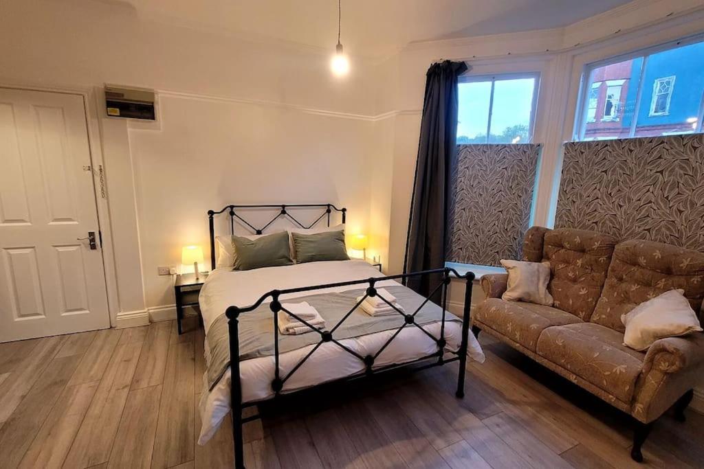 a bedroom with a bed and a couch at Sunnyside Studio Apartment in Llandrindod Wells