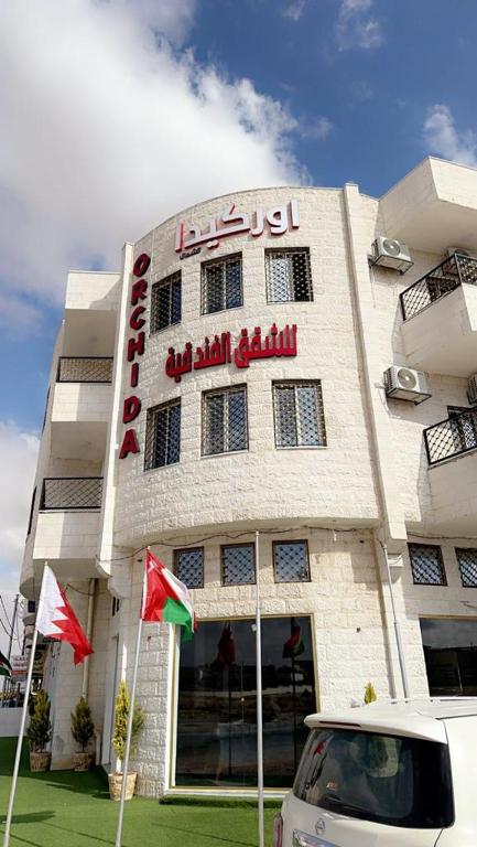 een witte auto geparkeerd voor een gebouw bij اوركيدا الشمال للشقق الفندقية in Al Mafraq