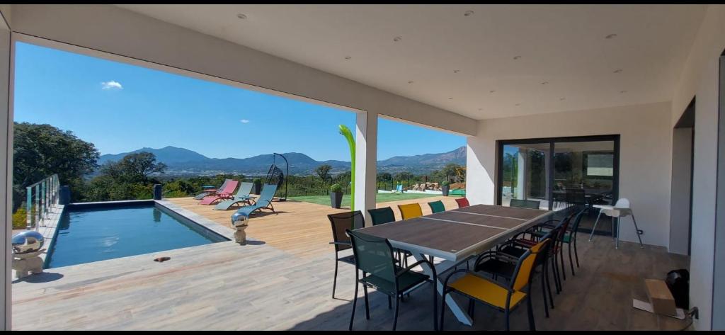 un patio con mesa y sillas y una piscina en Splendide Villa avec Piscine, Sauna, Jacuzzi Villa Cookini près d'Ajaccio, en Bastelicaccia