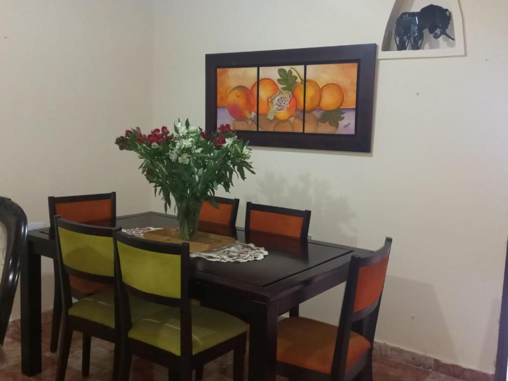 a dining room table with chairs and a vase of flowers at Victoria Brand apartahotel in Bogotá