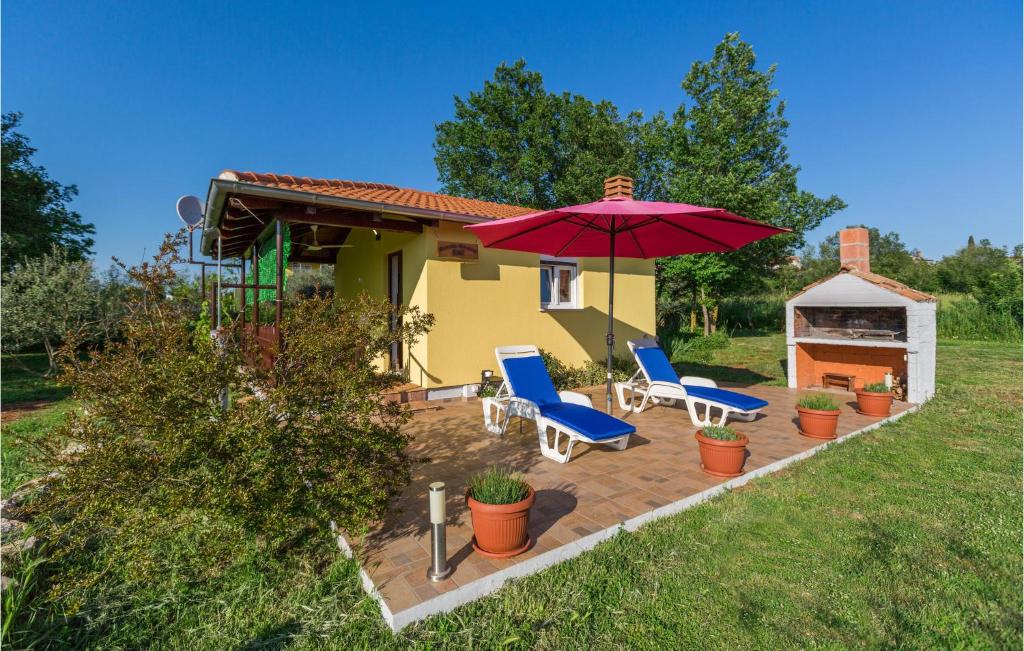 een patio met 2 stoelen en een rode parasol bij Nice Studio In Pula With Kitchen in Pula