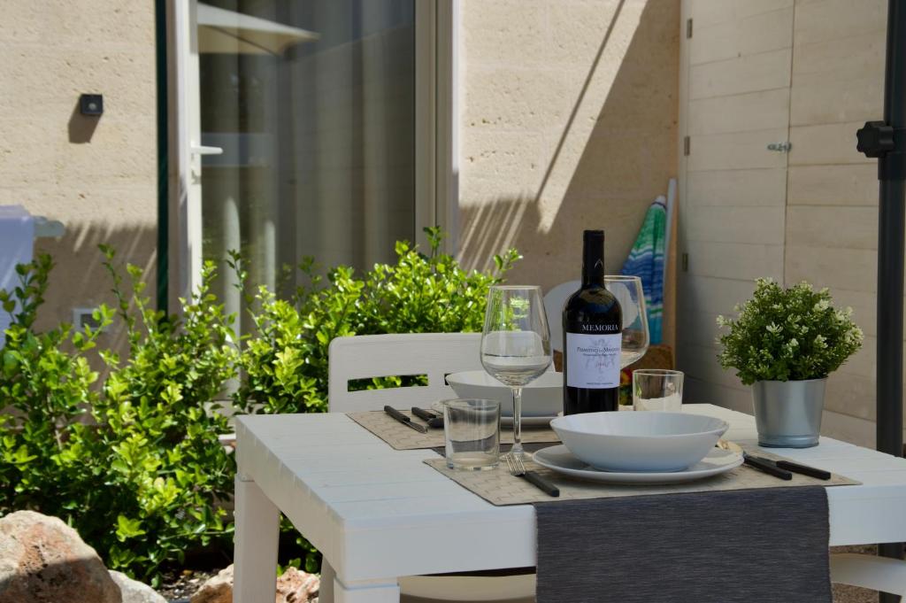 a white table with a bottle of wine and glasses at Casa Portacrànni in San Pietro in Bevagna