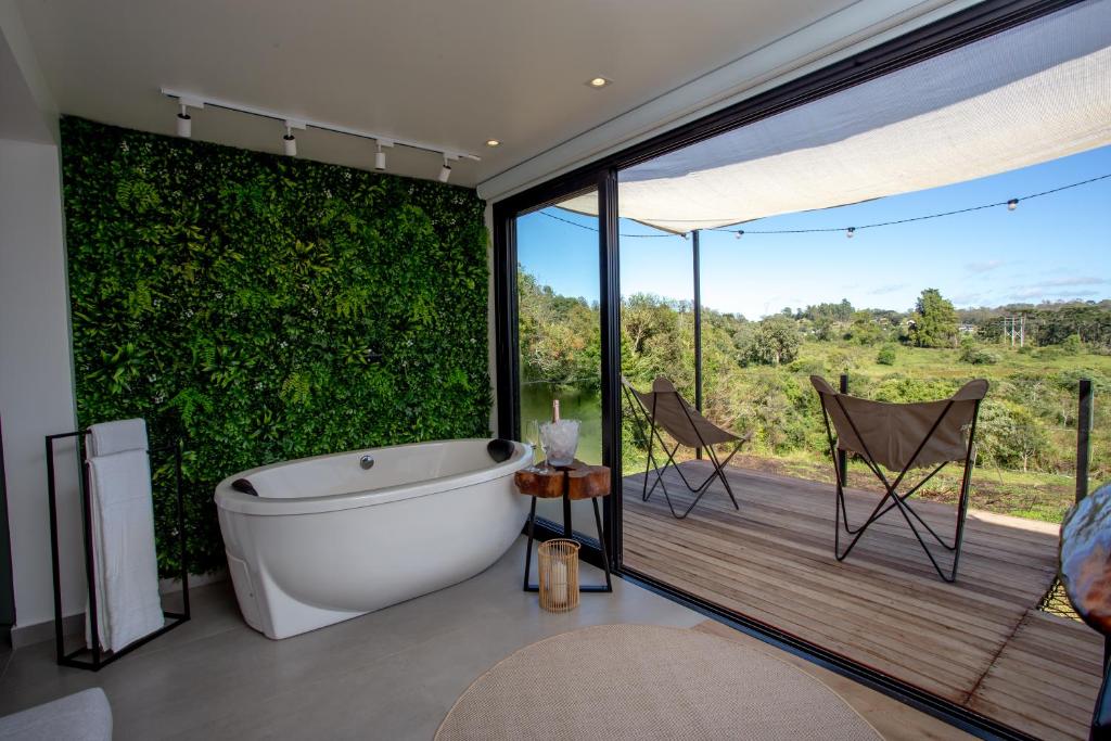 a bathroom with a tub and a balcony with a view at Casa Container - Haupt Village in Farroupilha