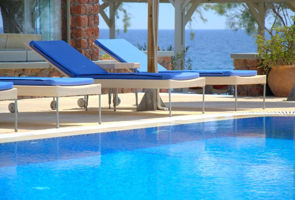 a swimming pool with blue chairs next to the water at Elixir Del Mar on the Beach in Kamari