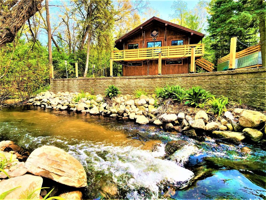 een blokhut met een rivier ervoor bij Beachside-HotTub-Fireplace-Authentically Northern in Traverse City