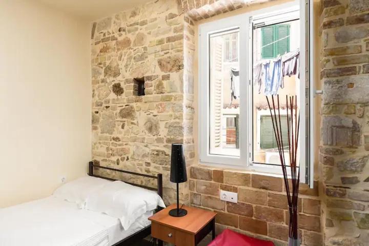 a room with two beds and a brick wall at Q Apartments in Corfu Town in Corfu