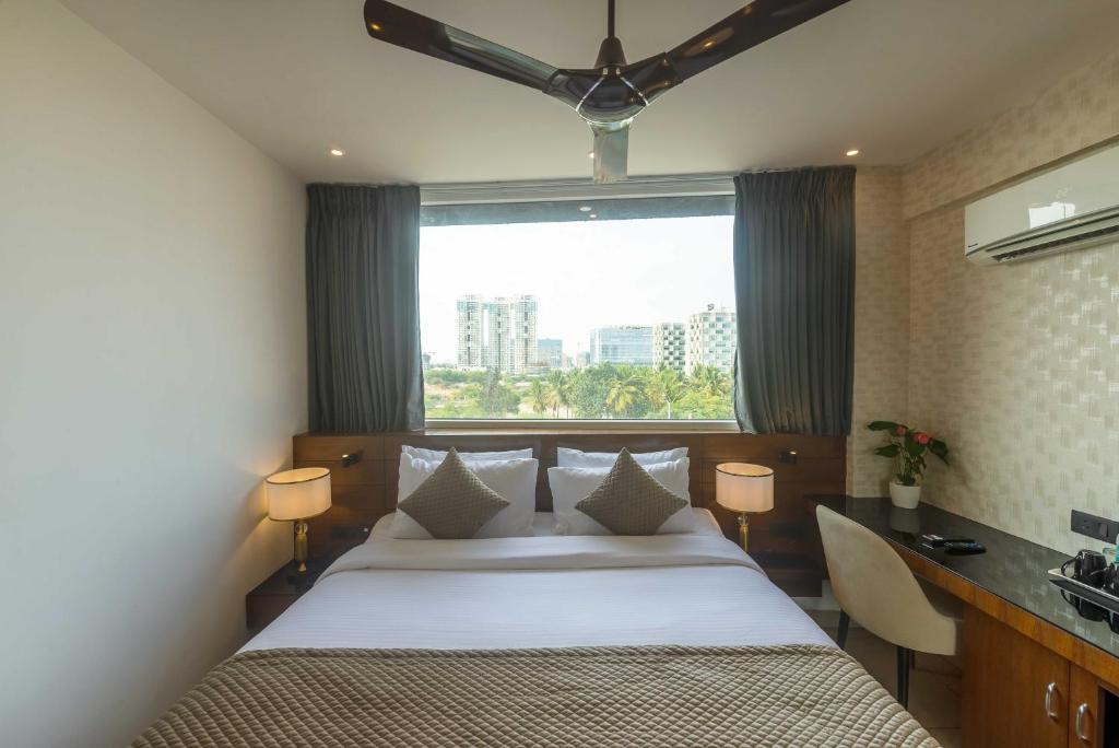 a bedroom with a bed and a desk and a window at Royal Ace Boutique Hotel - Manyata Techpark in Bangalore