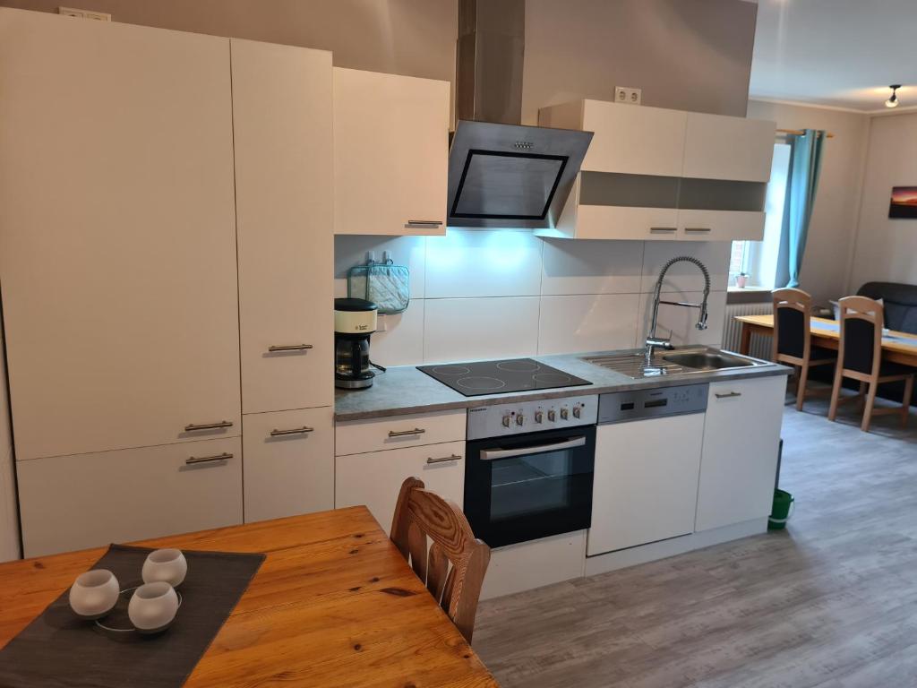 a kitchen with a stove and a sink and a table at Ferienwohnung mit Pool 2 in Nordleda