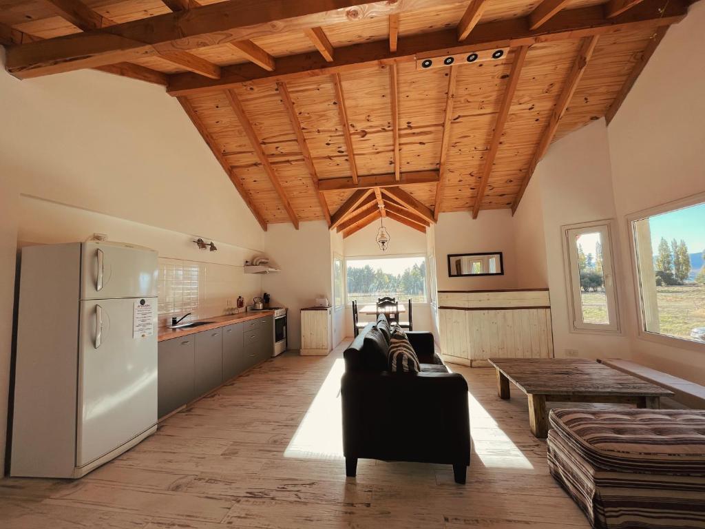 cocina y sala de estar con techos de madera y nevera. en Casa de Campo La Chacra en San Carlos de Bariloche