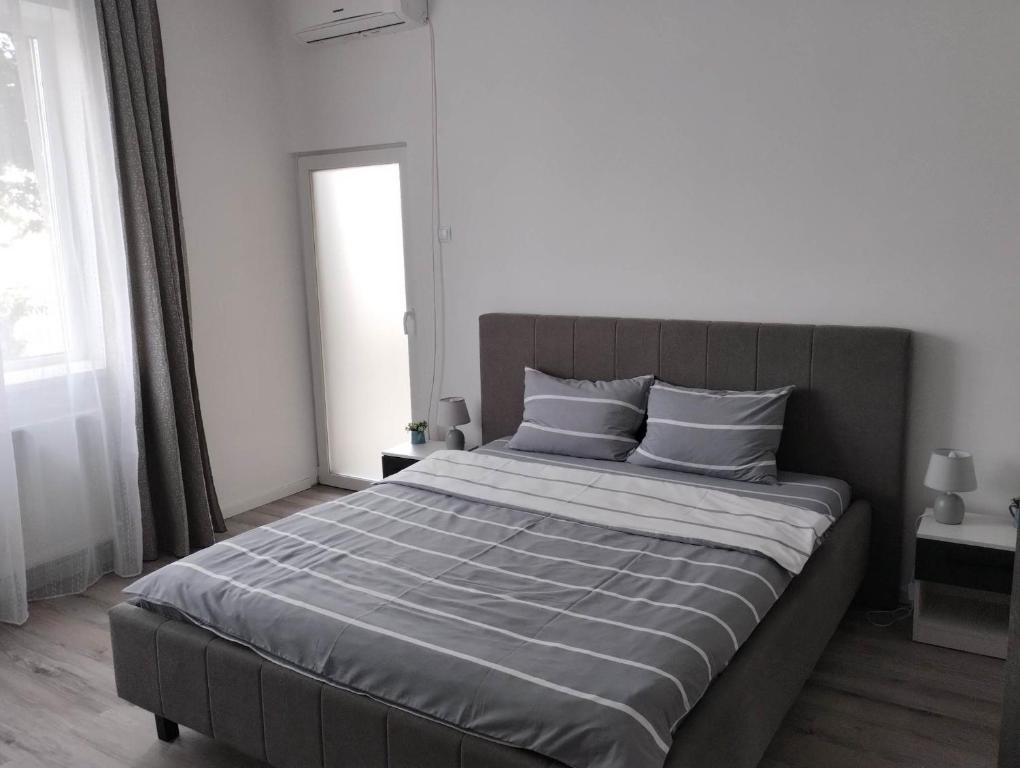 a large bed in a bedroom with a large window at Gigi Apartment in Cluj-Napoca