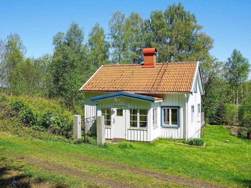 una pequeña casa blanca con techo rojo en un campo en Holiday home Fjällbacka IV, en Fjällbacka