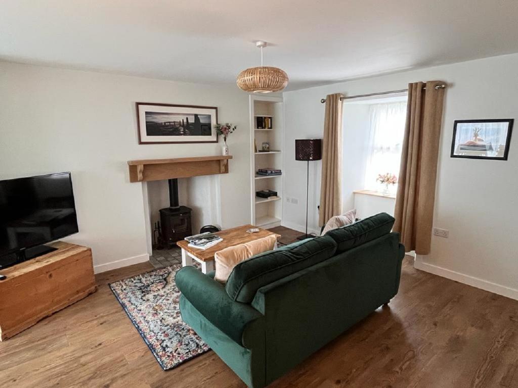 un soggiorno con divano verde e TV di Peedie Cott Self-Catering, Orkney a St Margaret's Hope