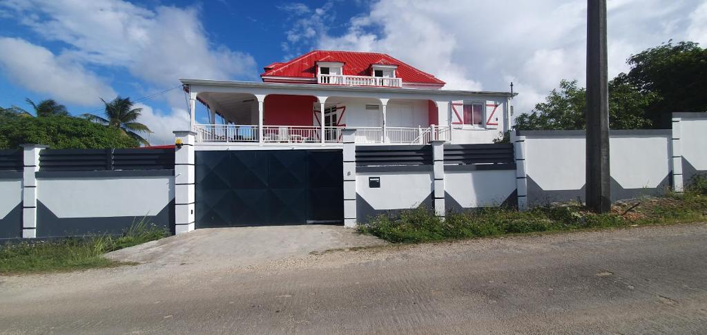 een wit huis met een rood dak met een hek bij Villa HAVA in Anse-Bertrand