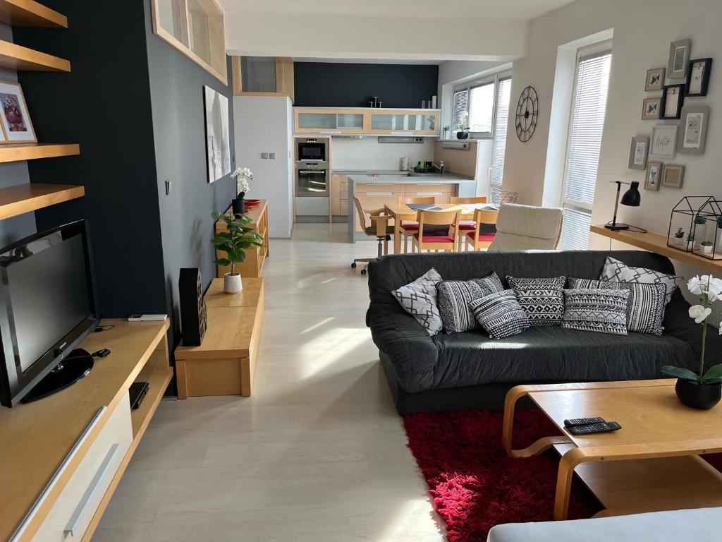 a living room with a black couch and a kitchen at Apartmán Dolné Bašty in Trnava