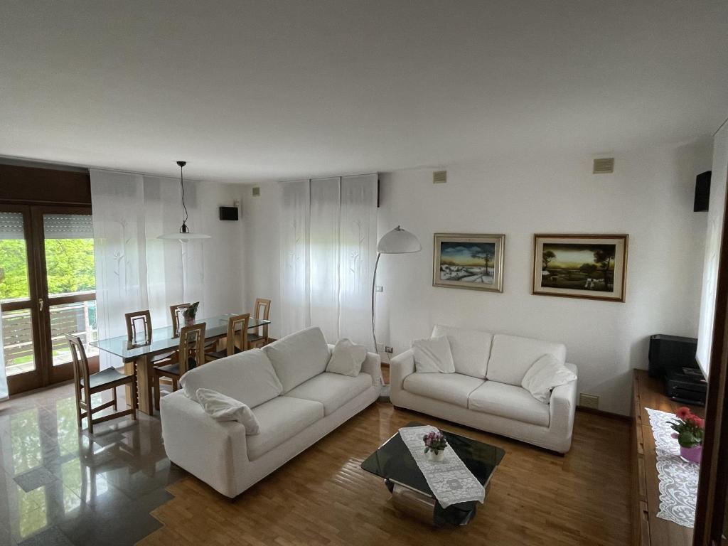 a living room with two white couches and a table at La Casa degli Orologi in Belluno