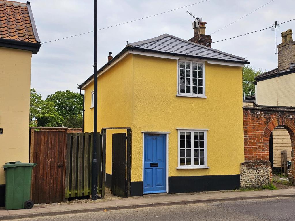 a yellow house with a blue door on a street at Perfectly Located Pretty Cottage in Diss