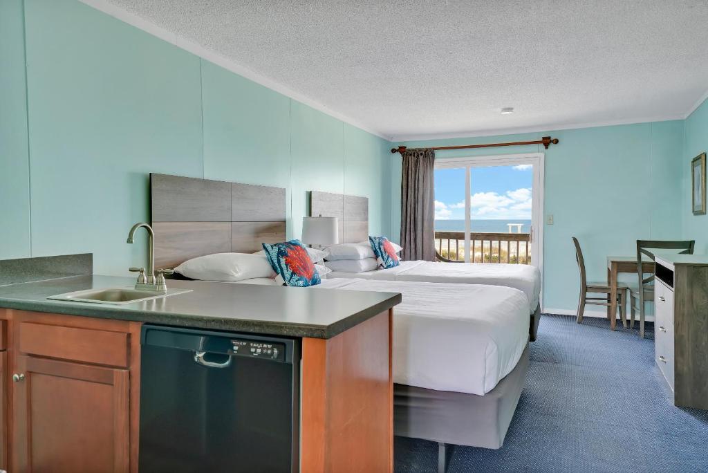 a bedroom with a bed and a kitchen with a sink at Admiral's Quarters in Kure Beach
