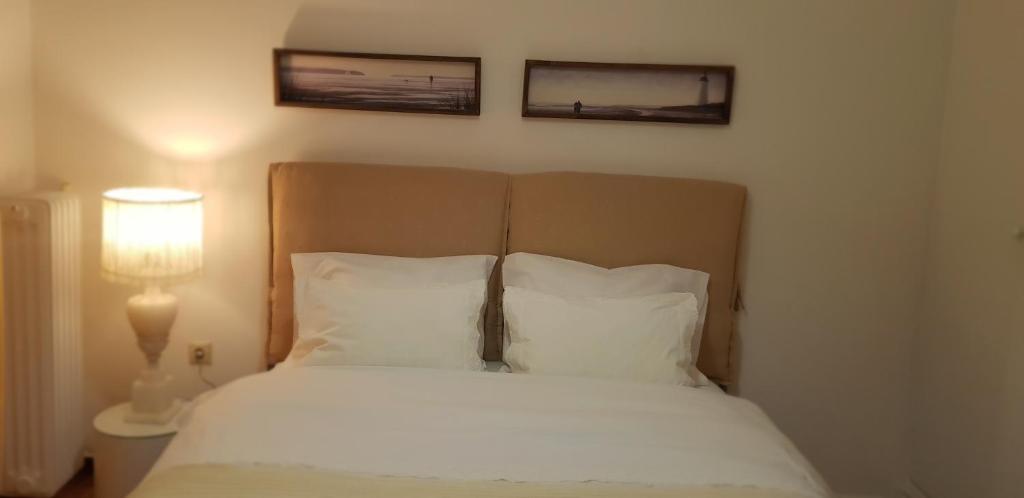 een bed met witte lakens en twee foto's aan de muur bij Comfy apartment in Athene