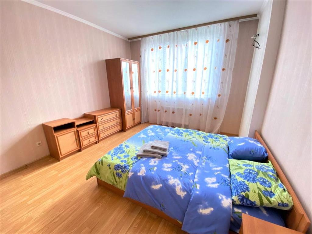 een slaapkamer met een bed met een blauw dekbed bij FlatService Двокімнатні апартаменти в ЖК "4 сезони" in Kiev