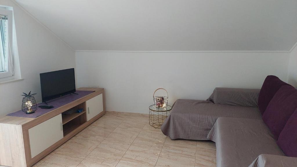 a small bedroom with a bed and a television at Apartments Nikola Caska in Novalja