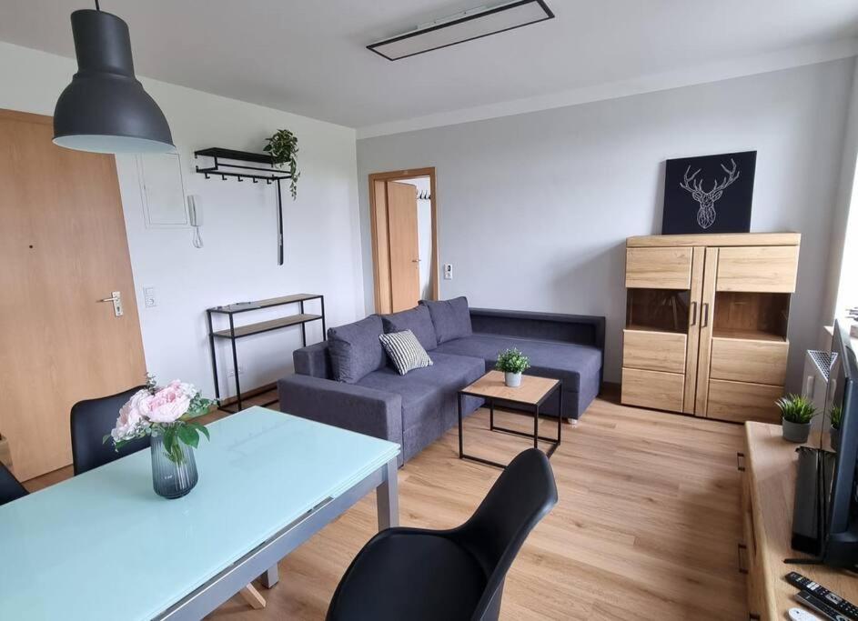 a living room with a blue couch and a table at Gemütliche Wohnung bei Leipzig in Schkeuditz