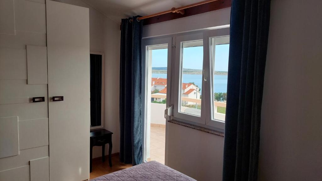 a bedroom with a window with a view of the ocean at Apartments Donadic I, Caska in Novalja