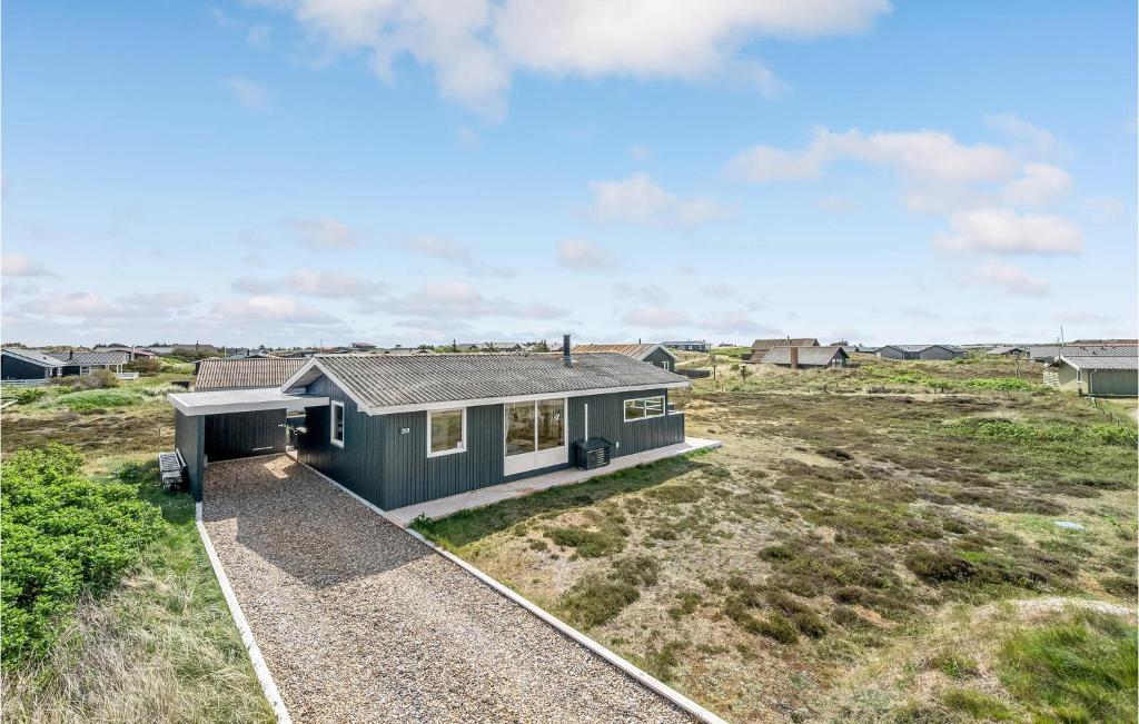 a green house on a grassy field with a house at Holiday Home Hvide Sande 31 in Bjerregård