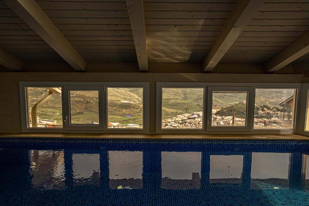 a swimming pool with windows and a view of a mountain at וילה לין בחרמון in Majdal Shams