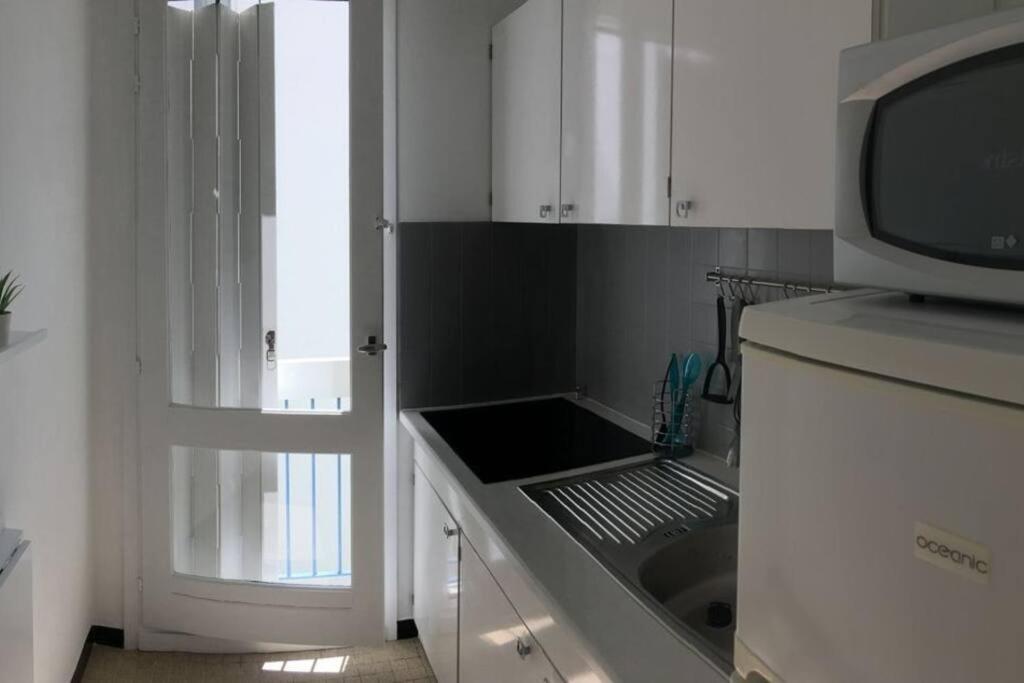 eine weiße Küche mit einer Spüle und einer Mikrowelle in der Unterkunft T2 très agréable et proche de la mer in La Grande-Motte