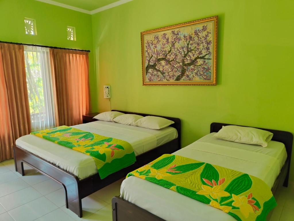 duas camas num quarto com paredes verdes em Berlian Inn Kuta Beach em Kuta