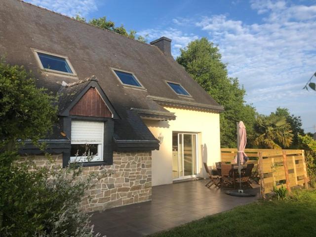 a house with a patio with a table and chairs at Maison près de Bon repos in Laniscat