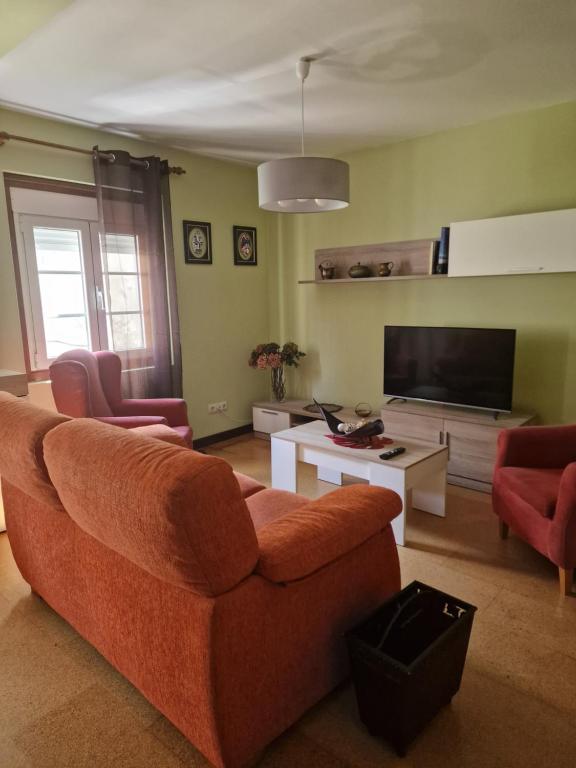 a living room with an orange couch and a tv at O Parrandeiro in Padrón