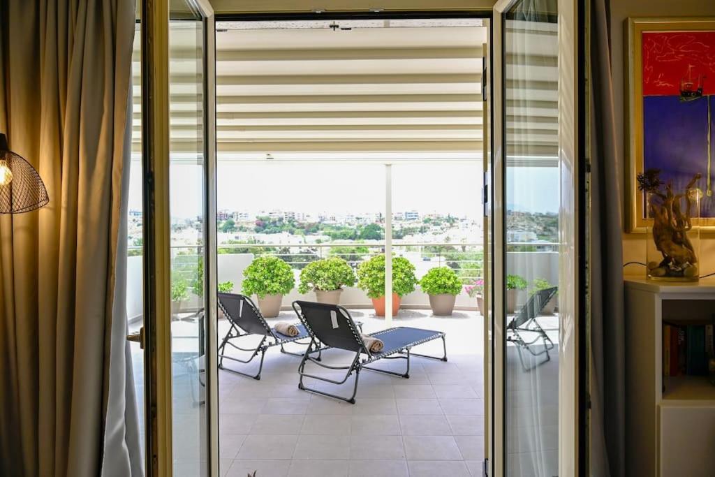 a room with a balcony with chairs and a table at Domus Vita Heraklio in Néa Alikarnassós